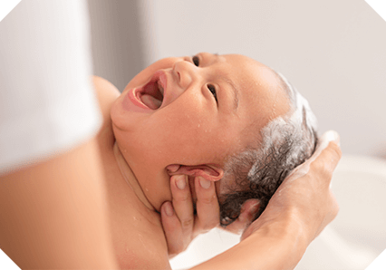 A baby having their head washed by a parent using Oilatum.